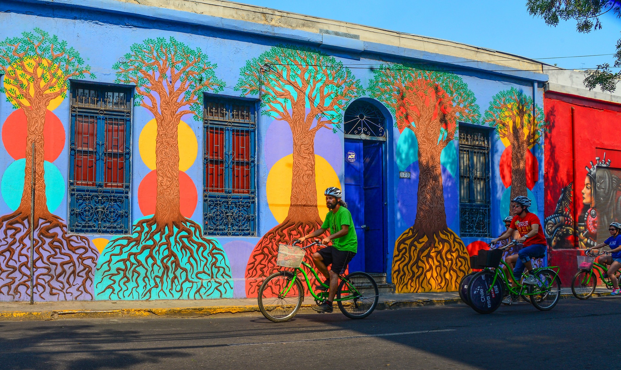 Tour group with La Bicicleta Verde biking past a colorful tree mural