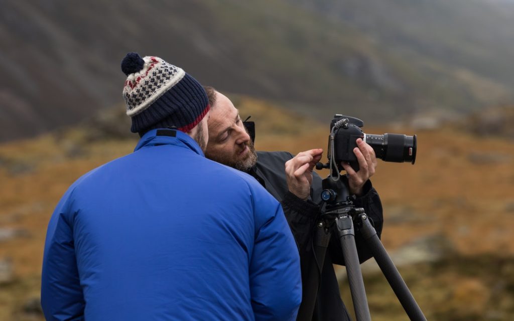 Unsplash stock photo of one man showing another man how to use a camera on a tripod